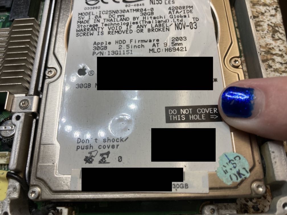 The old spinning-rust hard drive. There's an air-pressure-equalization vent hole near one edge, and the label has a section that says “DO NOT COVER THIS HOLE”. I'm mischievously covering it with my fingertip.