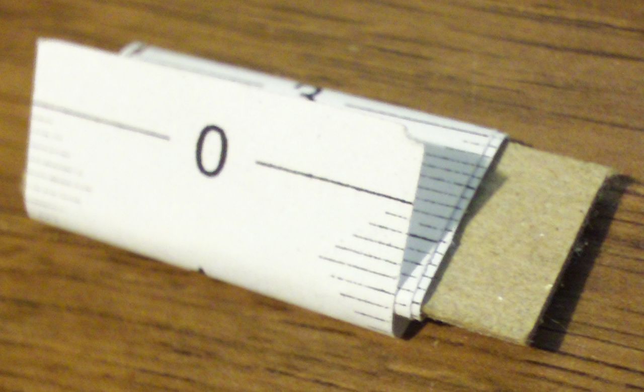 Photo of the portable centimetric measuring tape, rolled up, sitting on a table.