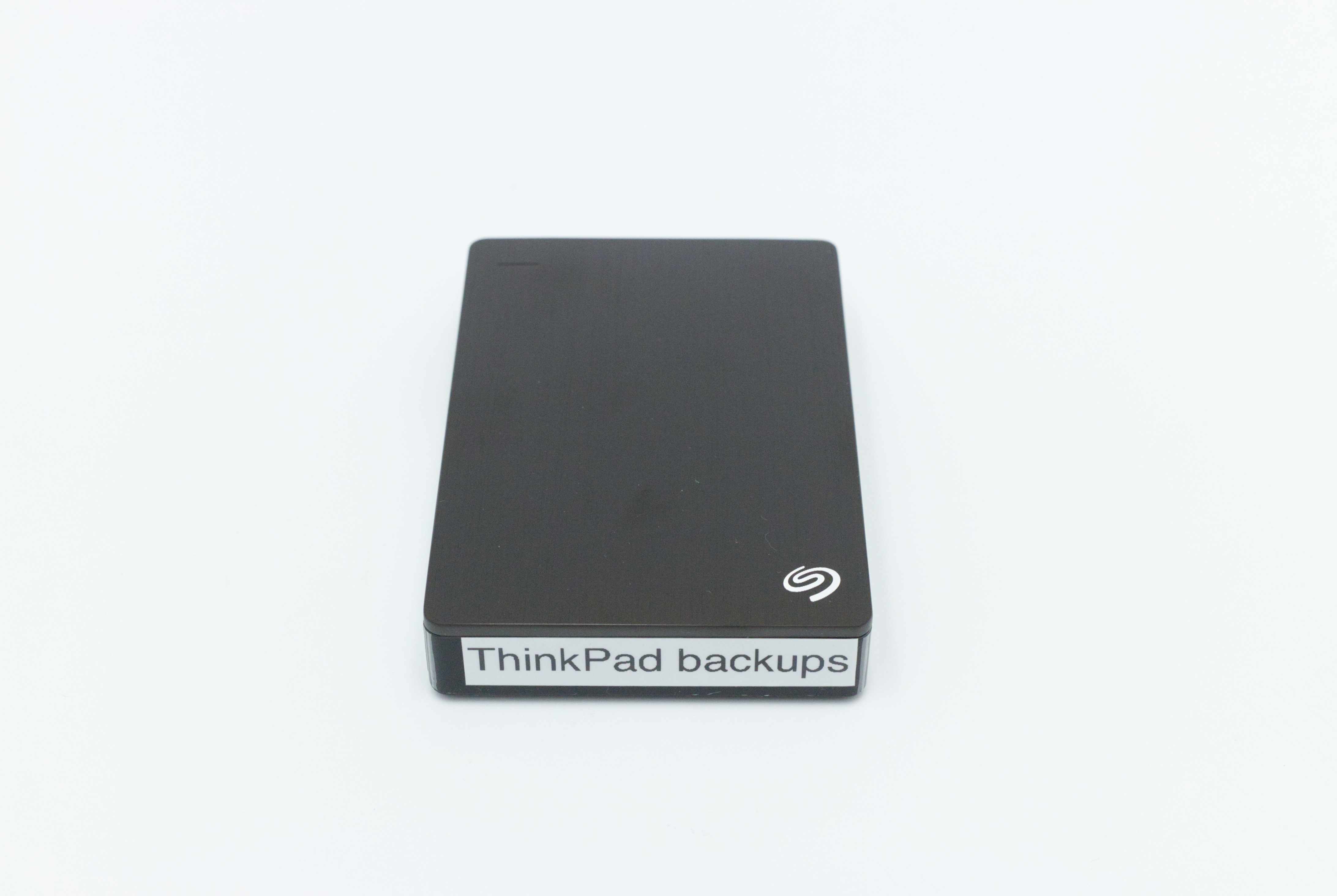 Front view of the real hard drive. The top face and front face are visible, and a label on the front reads “ThinkPad backups”.